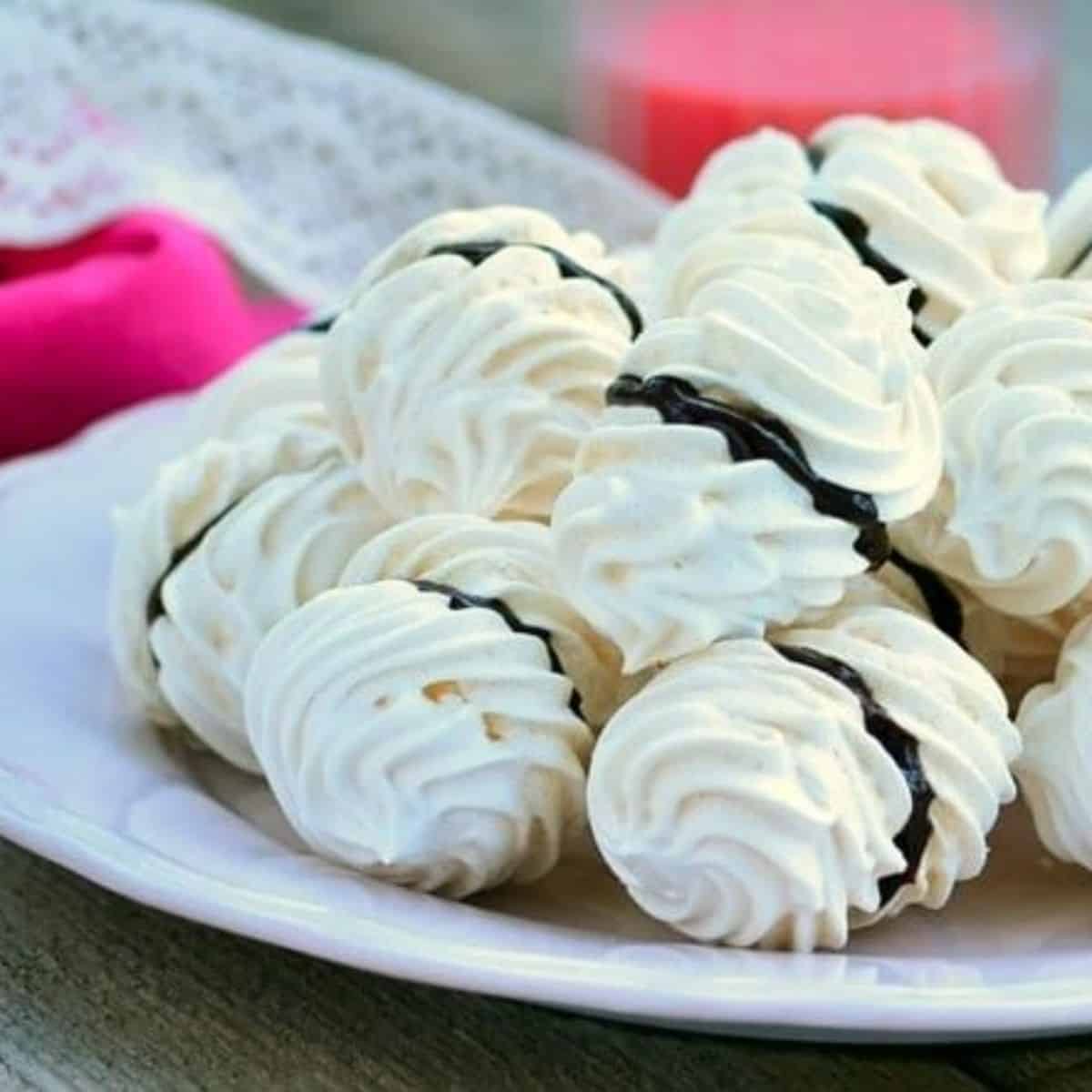 a plate of meringue cookies with chocolate cream.