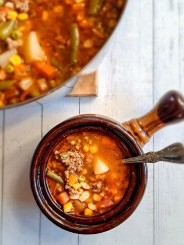 a large pot of vegetable soup and a small crock full.