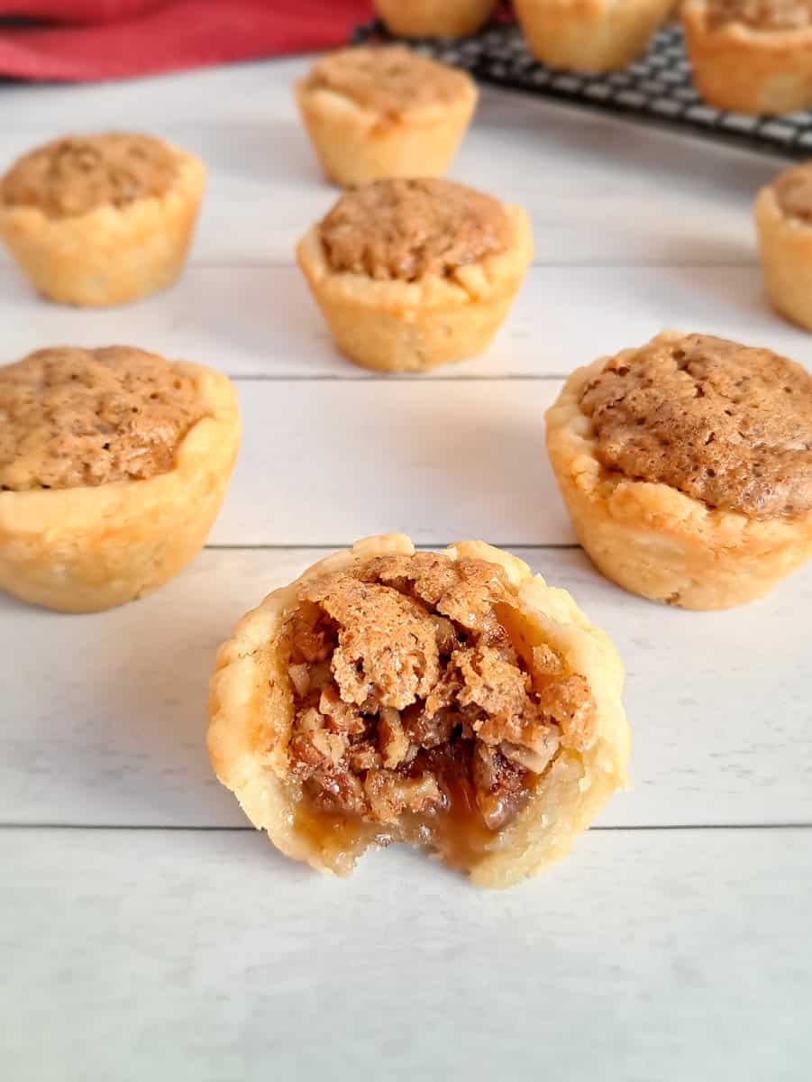 mini Amish pecan tarts scattered around, one has a bite out of it so you can see the filling.