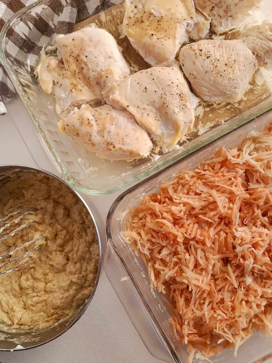 A pan with shredded potatoes, a pan with baked chicken breasts, and a saucepan with creamy sauce.