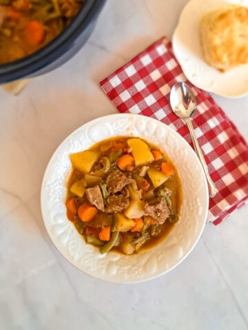 a bowl of Amish beef stew with a biscuit on a plate.