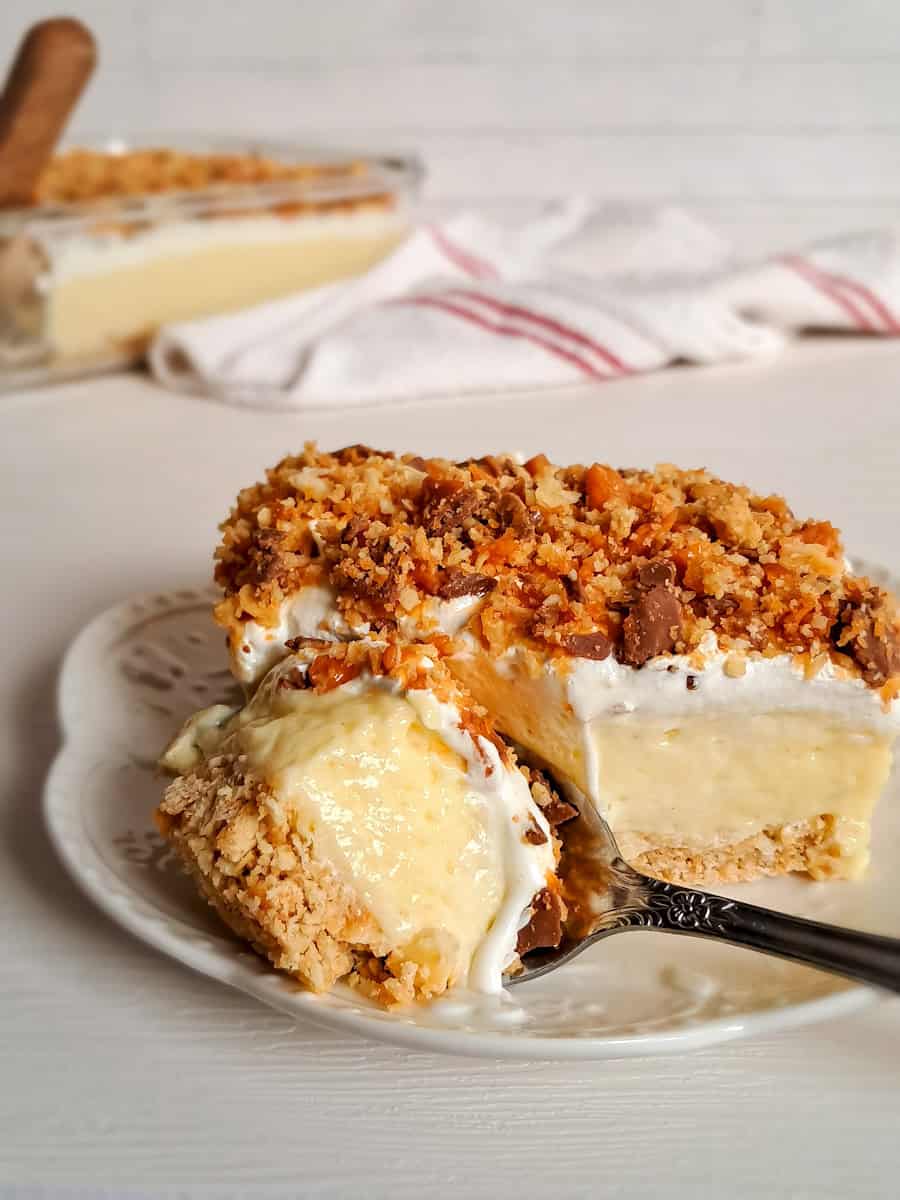taking a bite out of a slice of Amish butterfinger dessert on a small plate.