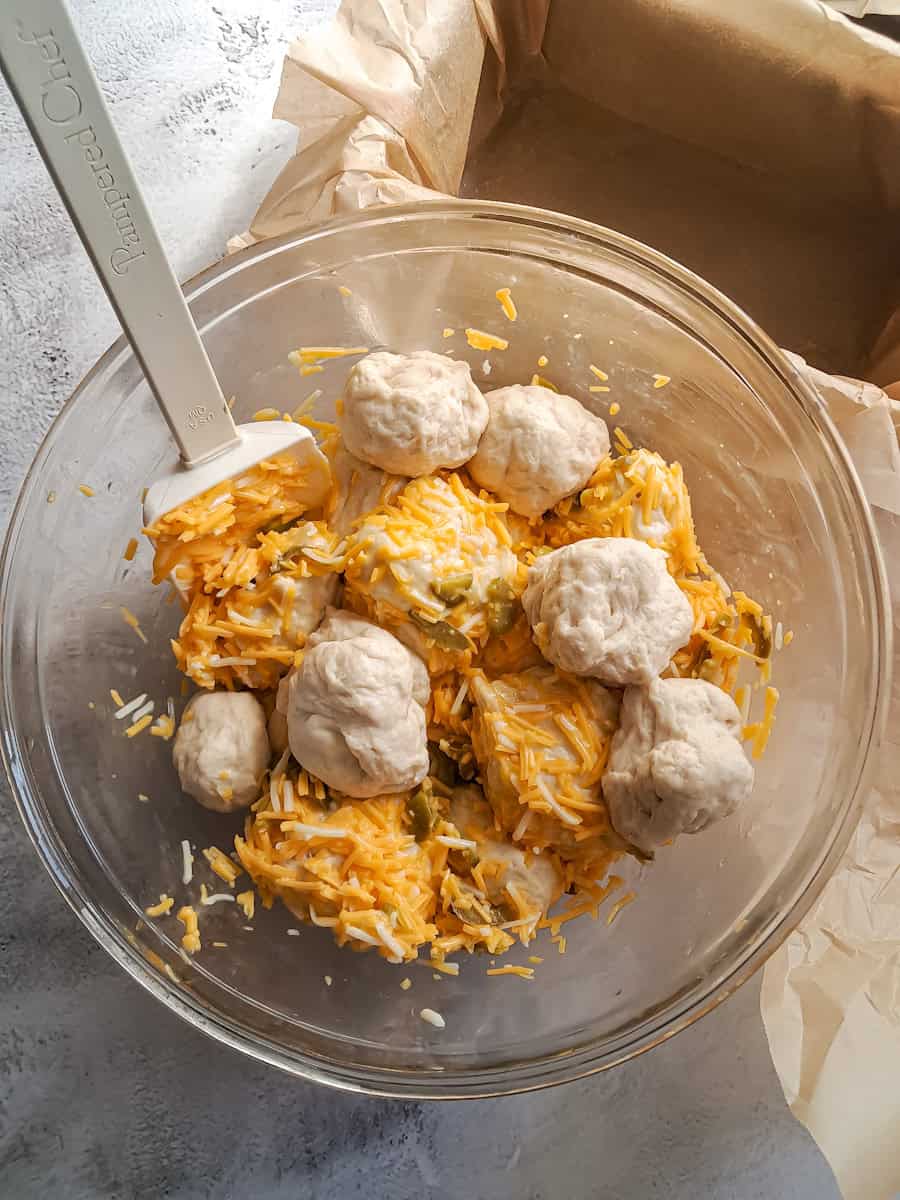 mixing bread dough balls with cheese mixture.