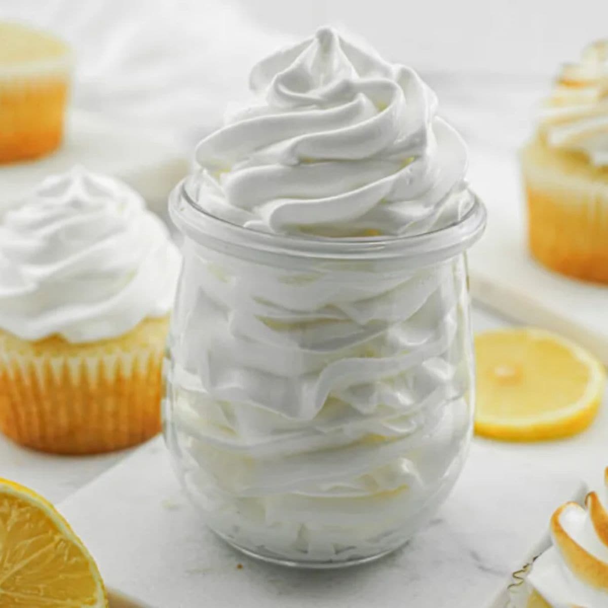 a glass container full of piped lemon marshmallow frosting.