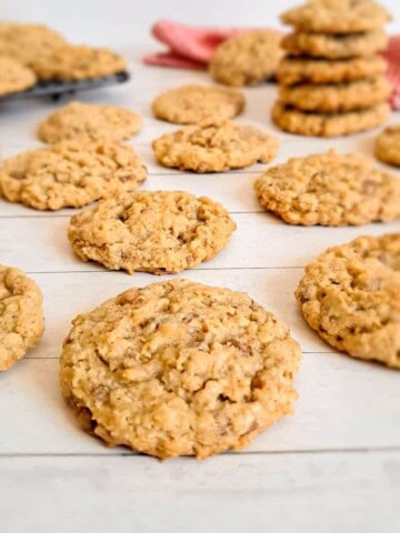 Amish toffee crunch cookies scattered around on white background.