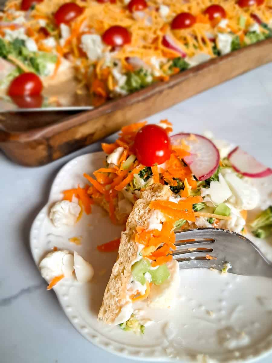 eating vegetable pizza with a fork, showcasing the crust and dressing underneath the veggies.