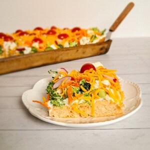 plate with crescent roll veggie pizza and pan full in background.