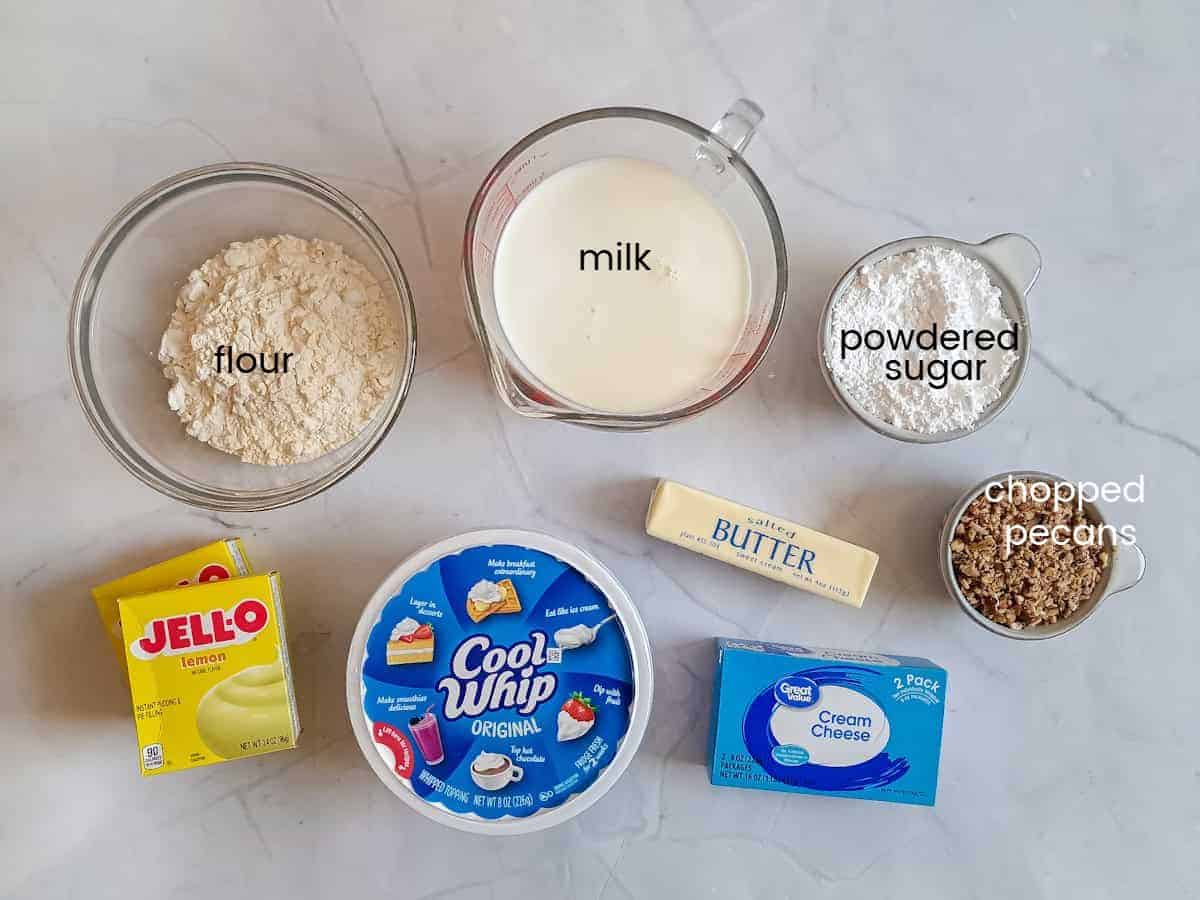 Ingredients: flour, powdered sugar, pecans, cream cheese, butter, milk, Cool Whip, and instant lemon pudding.
