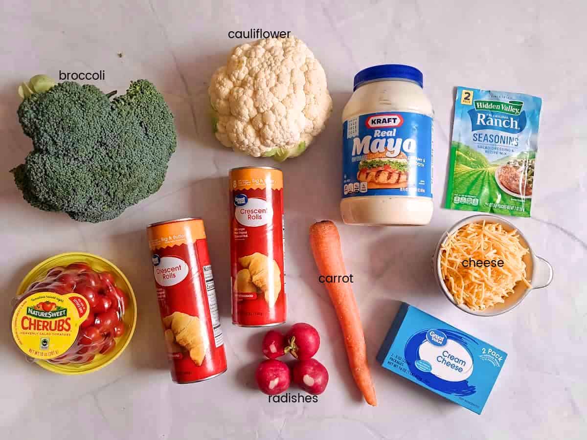 Ingredients: crescent rolls, Mayo, cream cheese, ranch, broccoli, cauliflower, carrot, radishes, cherry tomatoes, and cheese.