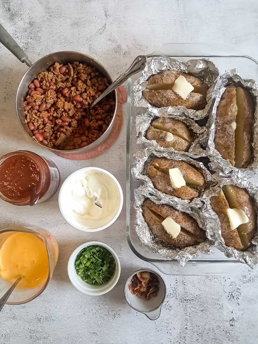 Baked potatoes with butter in a 9x13" dish and toppings around it.