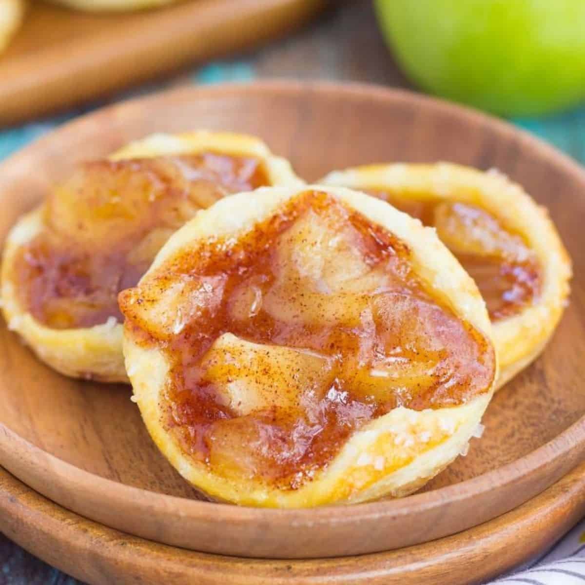 a wooden plate with caramel apple danishes.