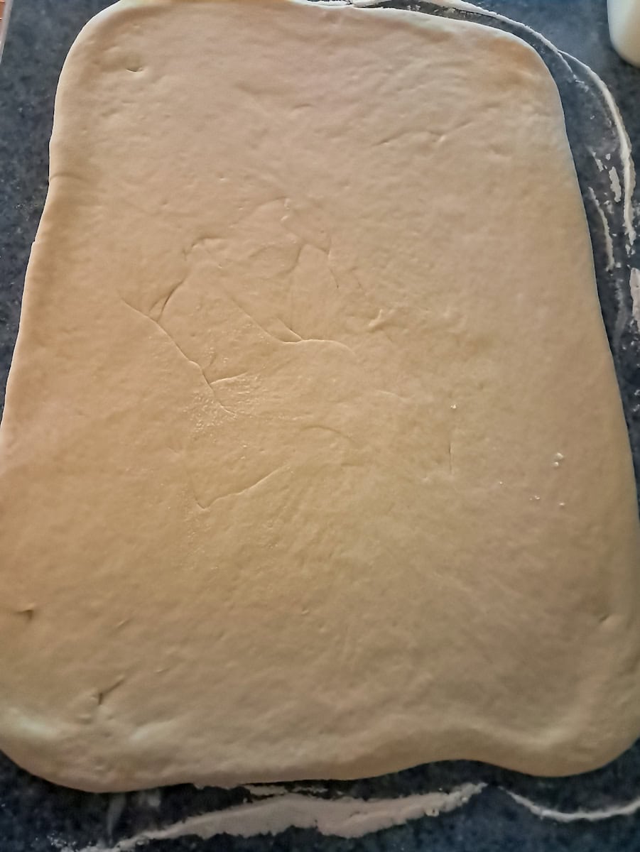 dough is rolled out into a rectangle on floured surface.