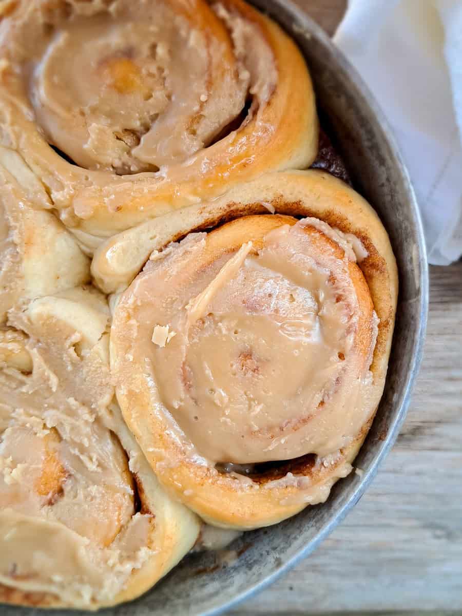 a round pan full of cinnamon rolls ready to eat.