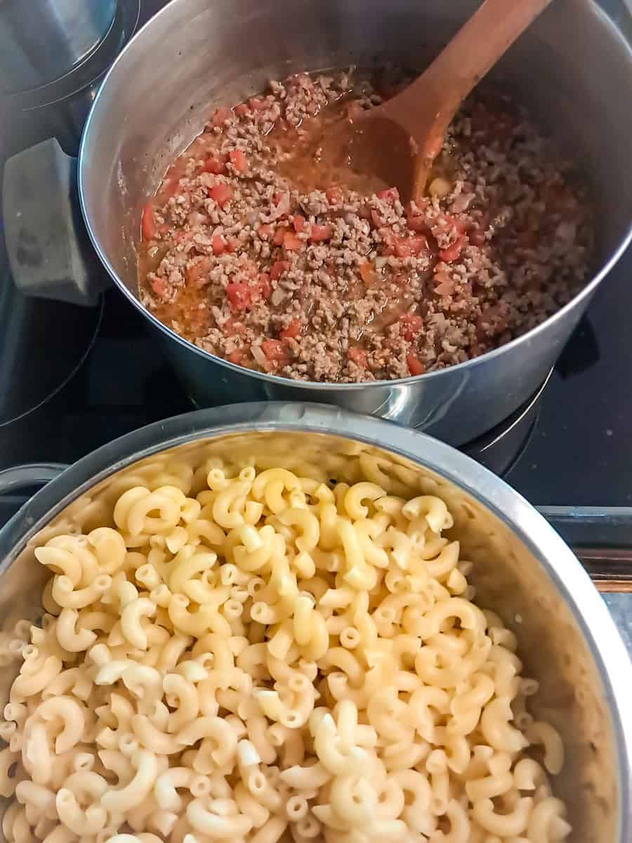 macaroni draining in a colander, and a pot of beef and tomato.