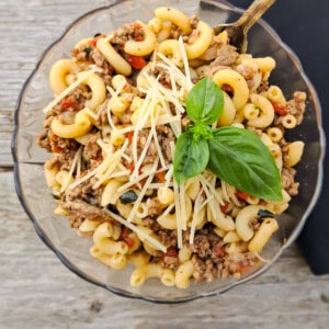 a bowl of Amish macaroni and tomato topped with a bit of parmesan cheese and basil.