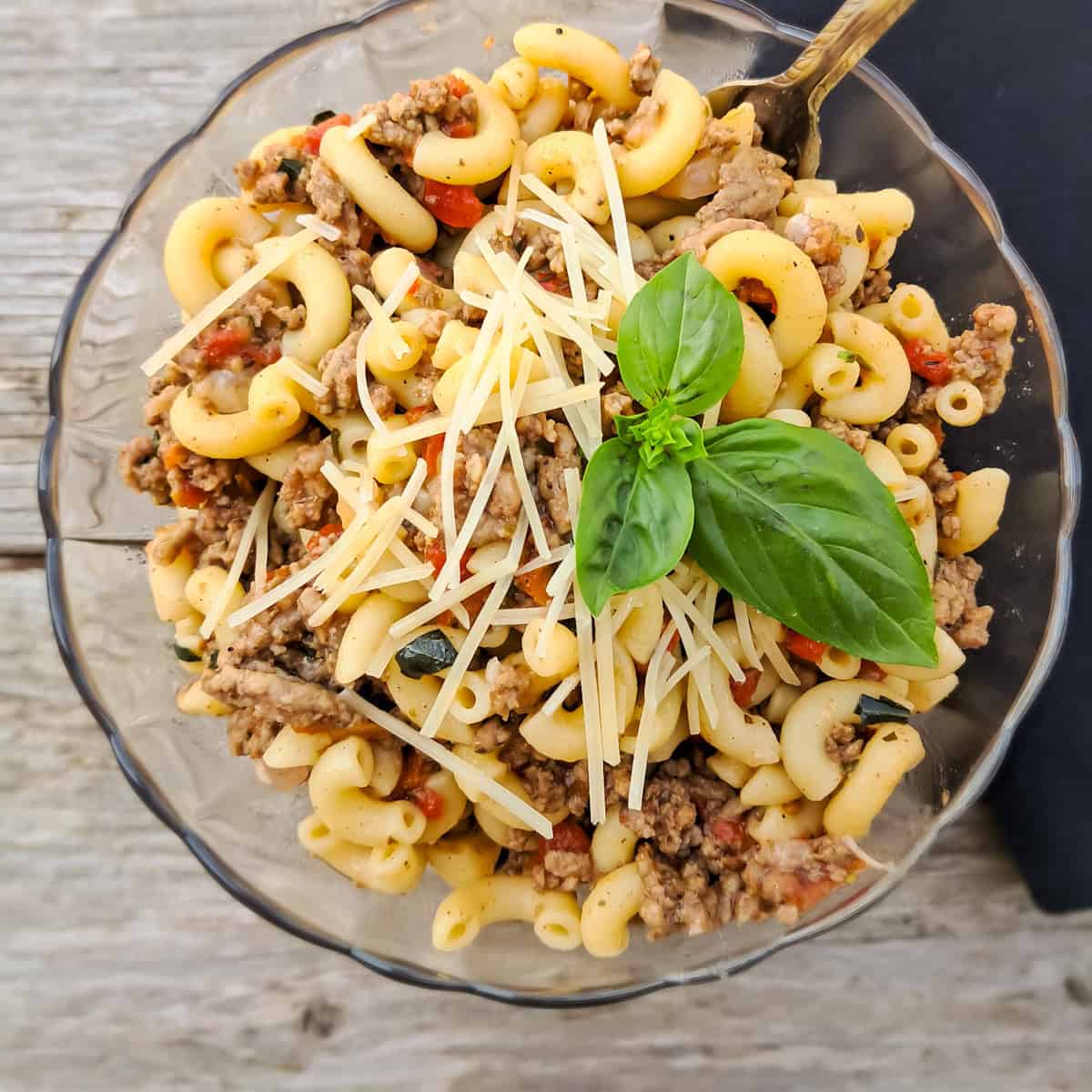 a bowl of Amish macaroni and tomato topped with a bit of parmesan cheese and basil.