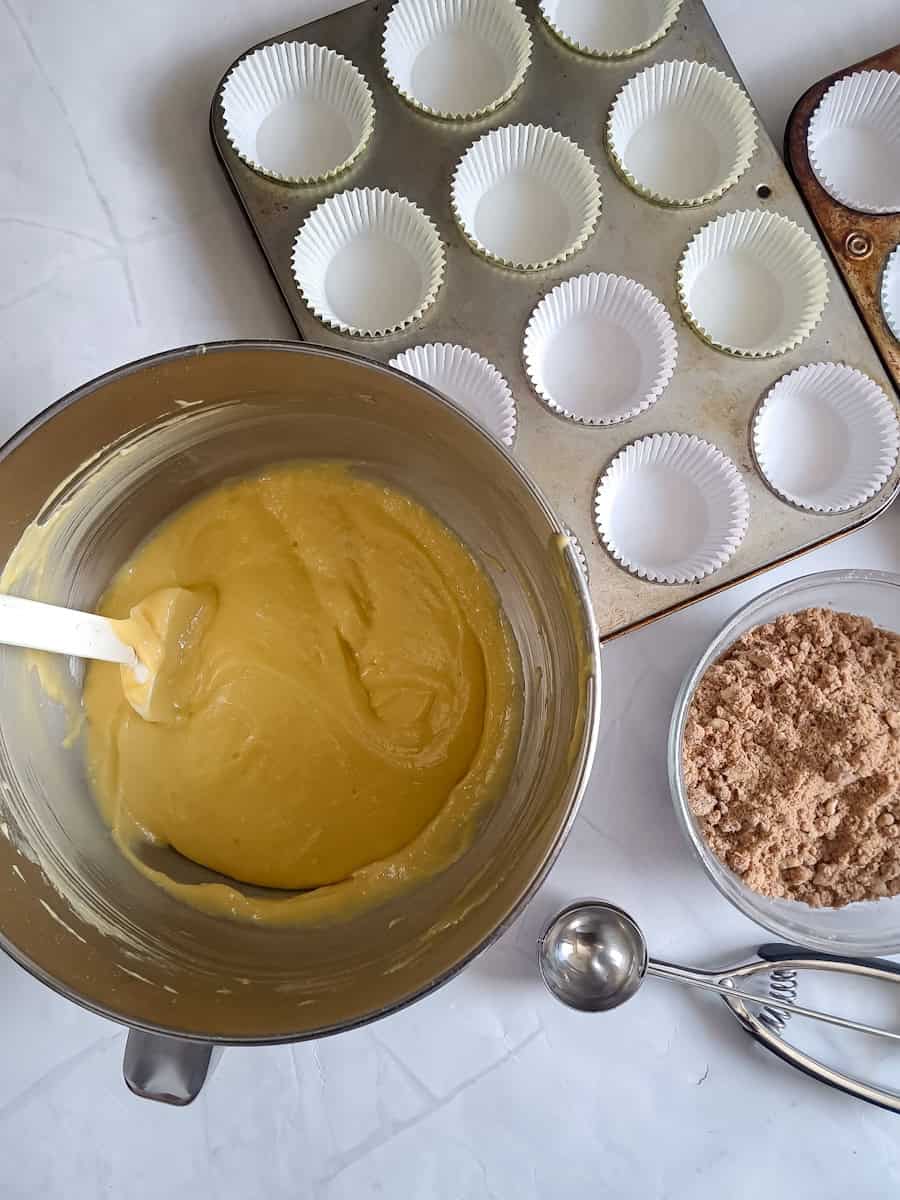 cake batter in a bowl, muffin tins ready to be filled, and streusel crumbs in another bowl.