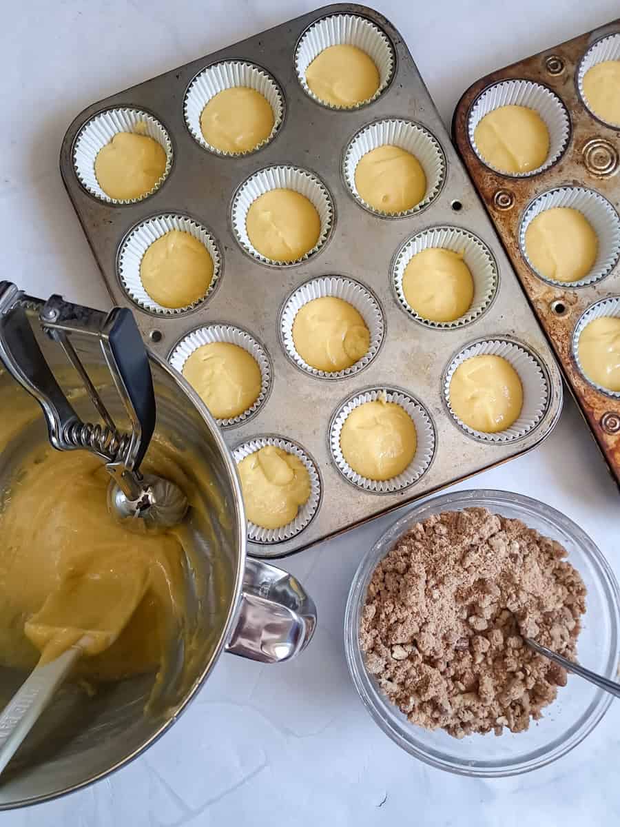 muffin tins with some batter in and now we are ready to sprinkle cinnamon crumbs over the top.