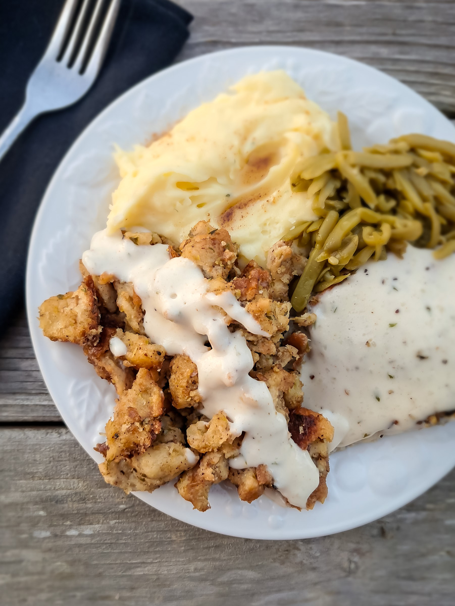 a plate full of yummy looking food: stuffing, mashed potatoes, chicken, and green beans.