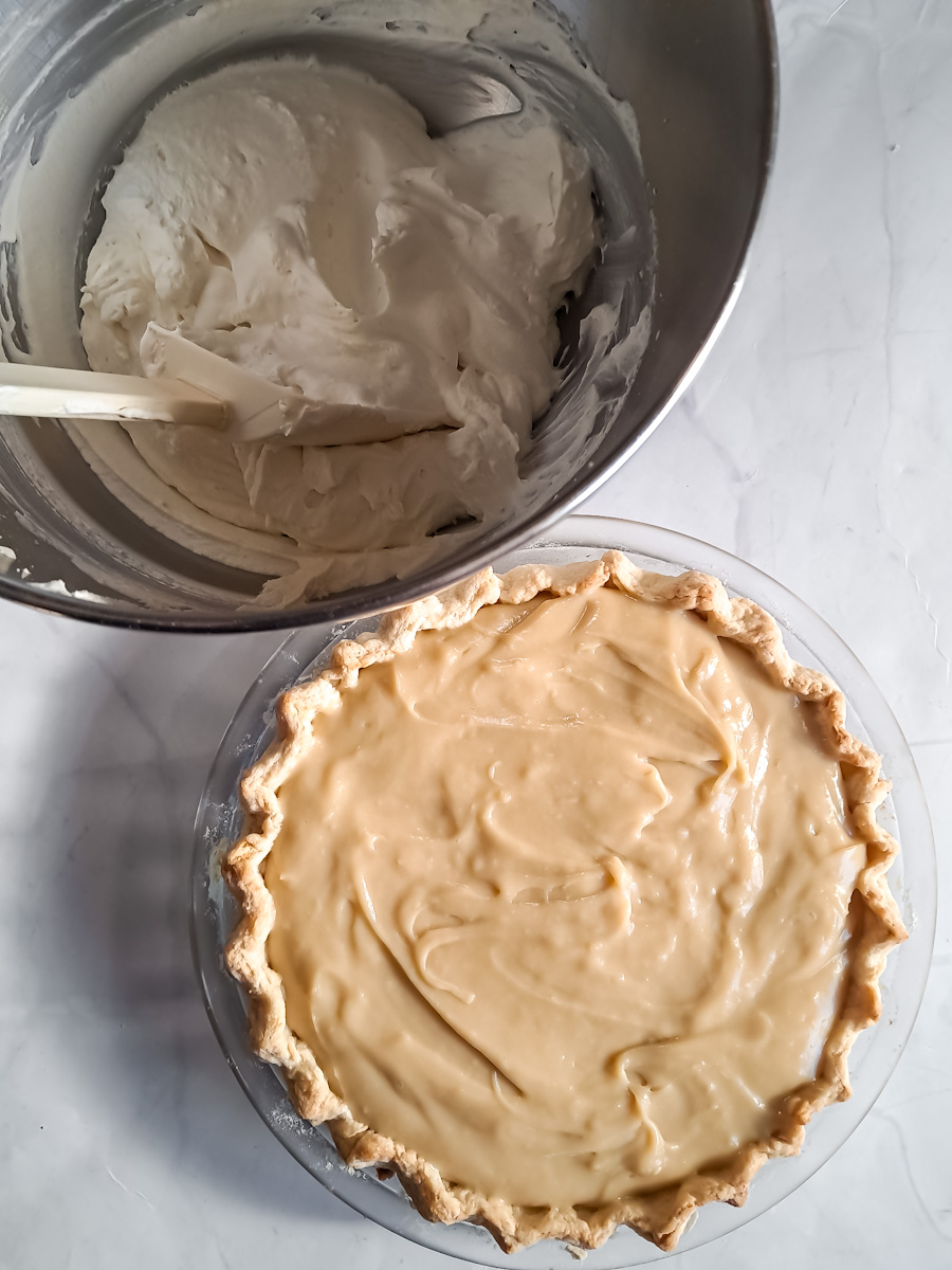 whipped cream in a bowl, ready to top the homemade butterscotch pie.