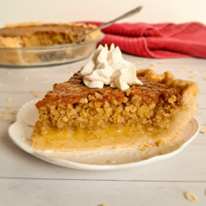 a slice of Amish oatmeal pie on a small plate with the remining pie in the background.
