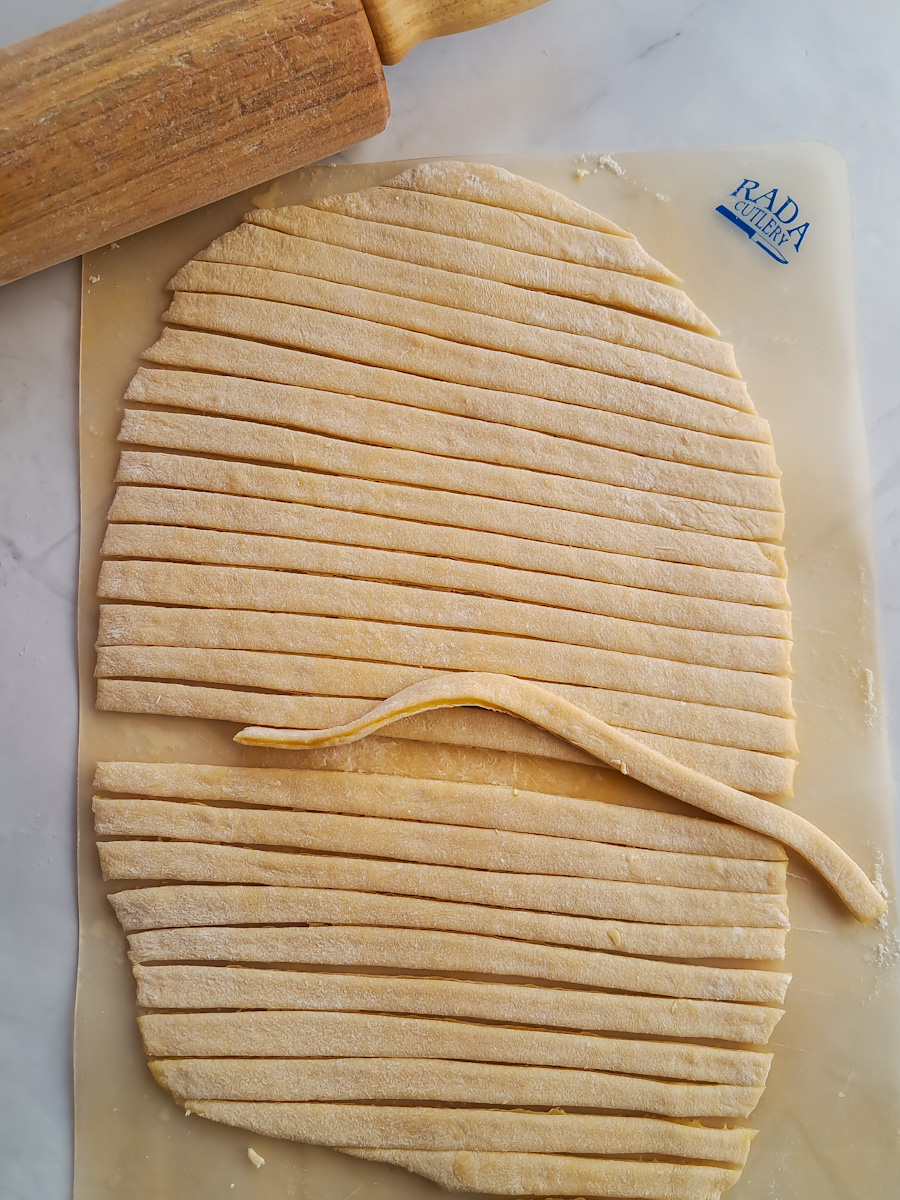 cutting rolled out noodle dough into strips to make noodles.
