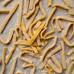 Homemade noodles scattered on parchment paper.