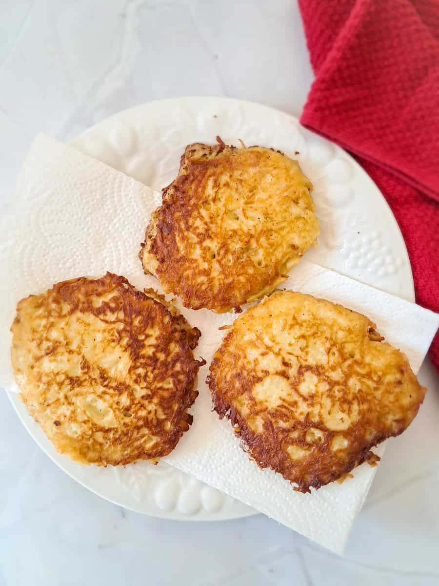 fried pancakes on a paper towel lined plate.