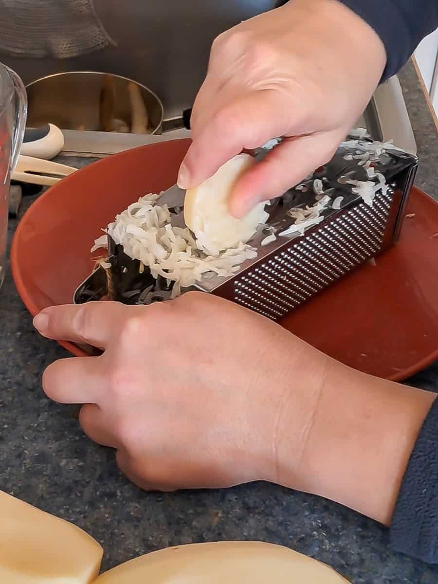 grating potatoes with a box grater.