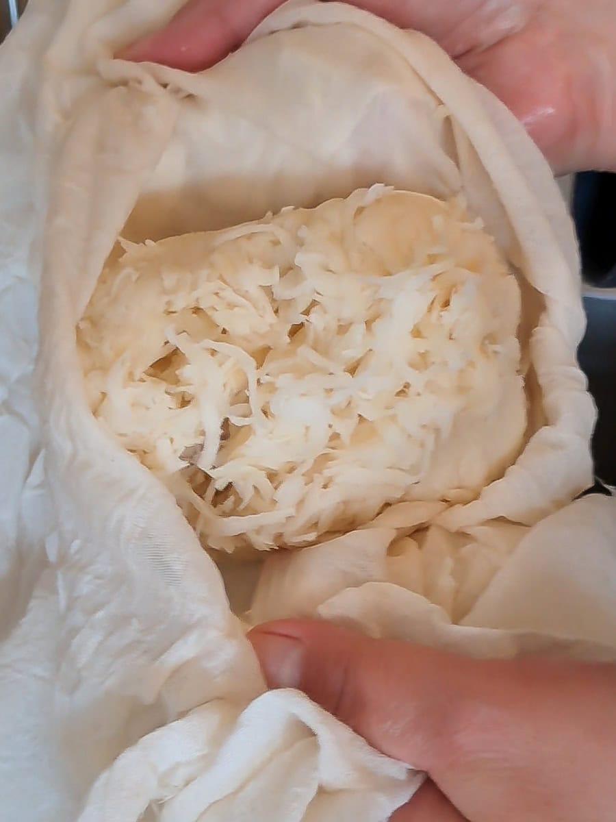 grated potatoes in a cheese cloth ready to add to batter.