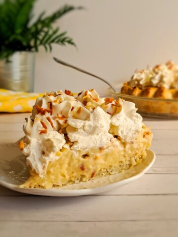 featuring a slice of Amish coconut cream pie with whipped cream and toasted coconut flakes.