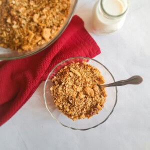 oats and butterscotch granola cereal in a glass bowl ready to eat with a jar of milk.