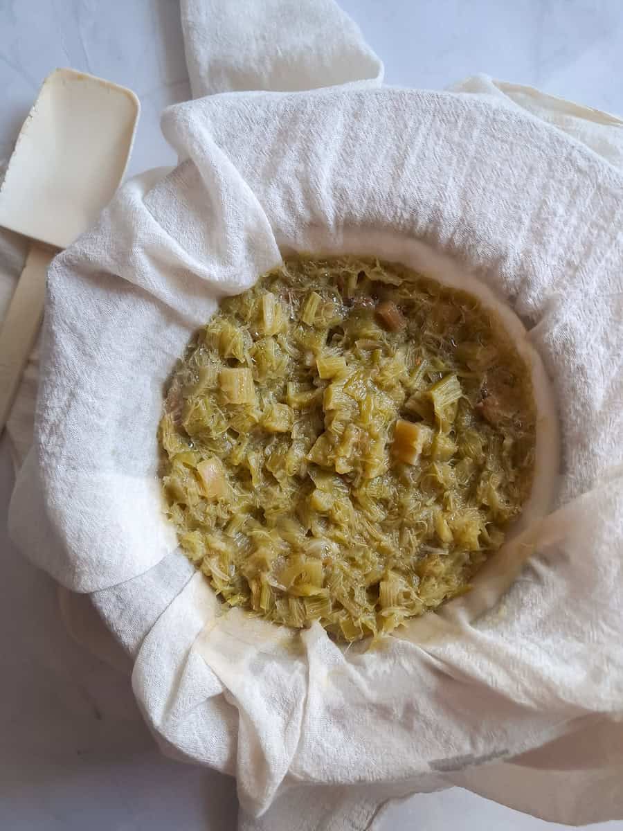 straining the cooked rhubarb juice through a cheesecloth.