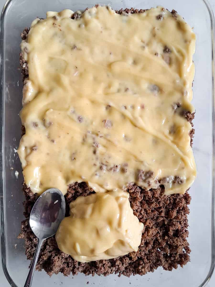 browned beef spread into a 9x13" glass pan and now we are spreading the cream soups over the top.