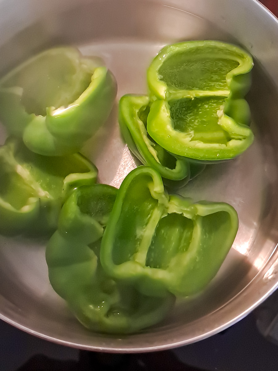 boiling green bell peppers in water to soften.