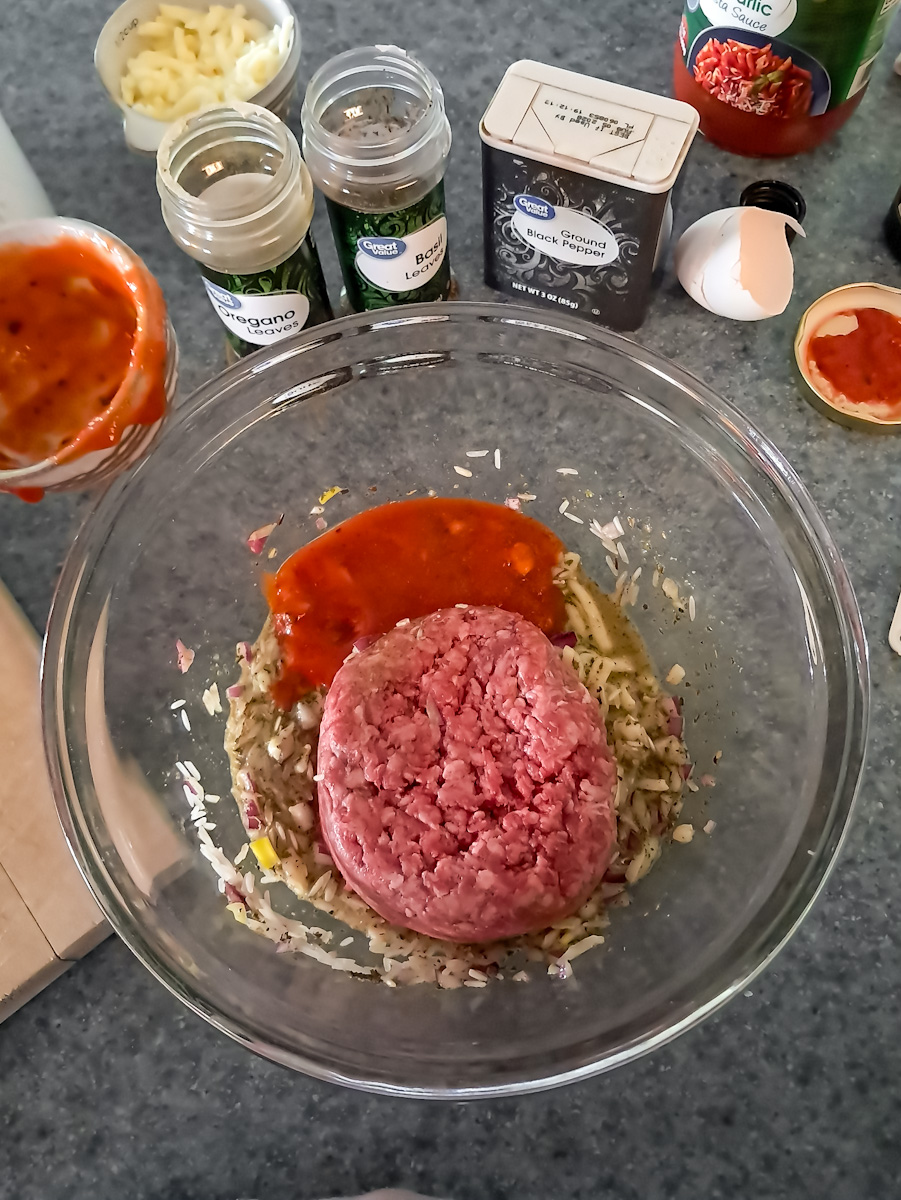 Mixing the ground beef and seasonings with sauce and egg in a small bowl.