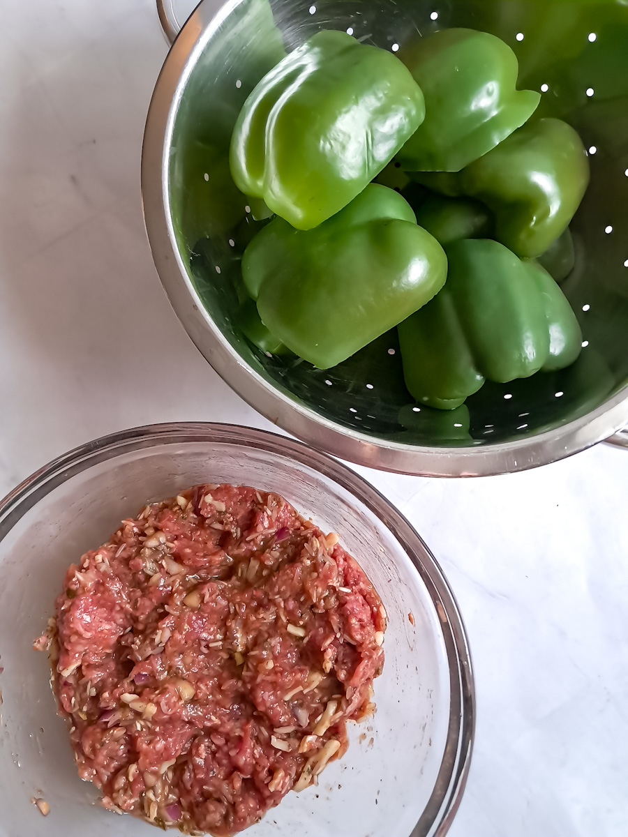 draining the boiled peppers in a colander, and the ground beef mixture in another bowl.
