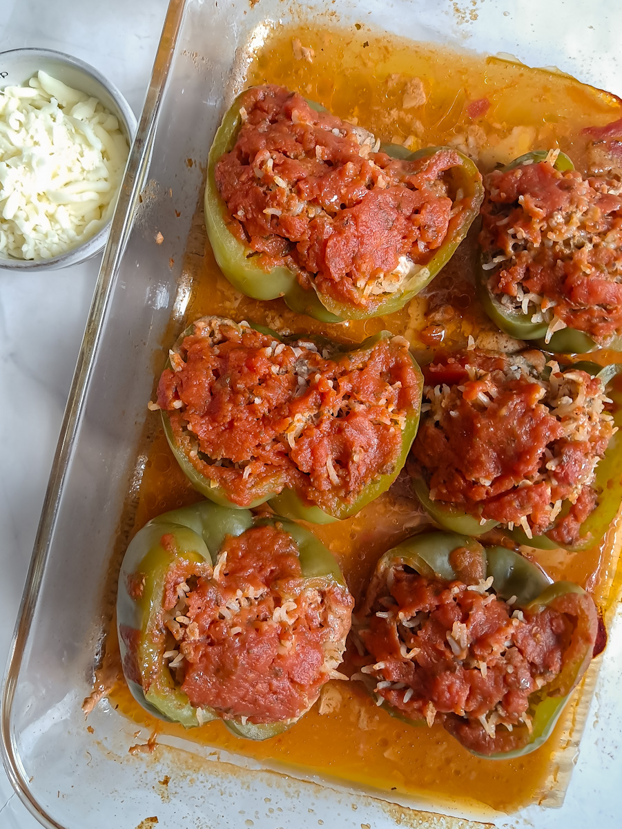partially baked stuffed peppers ready to spread cheese on top.