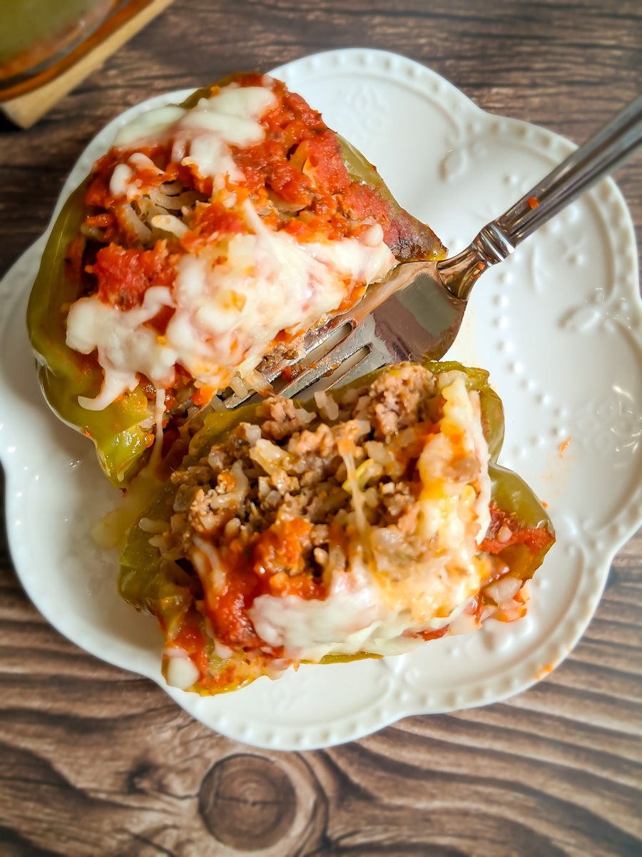 a baked green pepper stuffed with ground beef and rice mixture, cut in half on a plate.