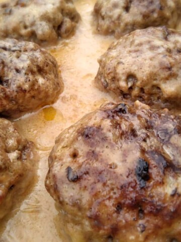 a close-up look at a pan of poor mans steak patties in mushroom gravy - an easy and affordable ground beef favorite.