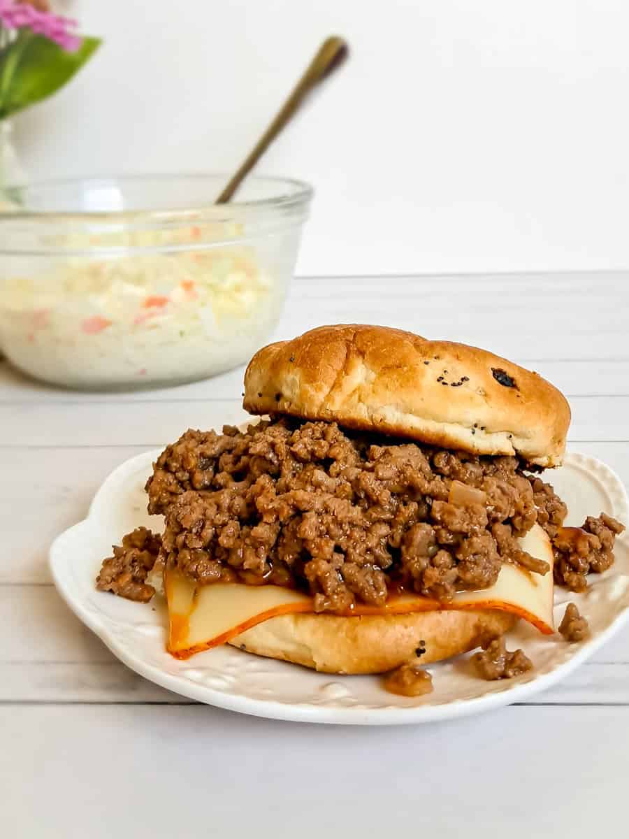 close-up look at a sandwich with homemade sloppy joe filling, and a big bowl of coleslaw.