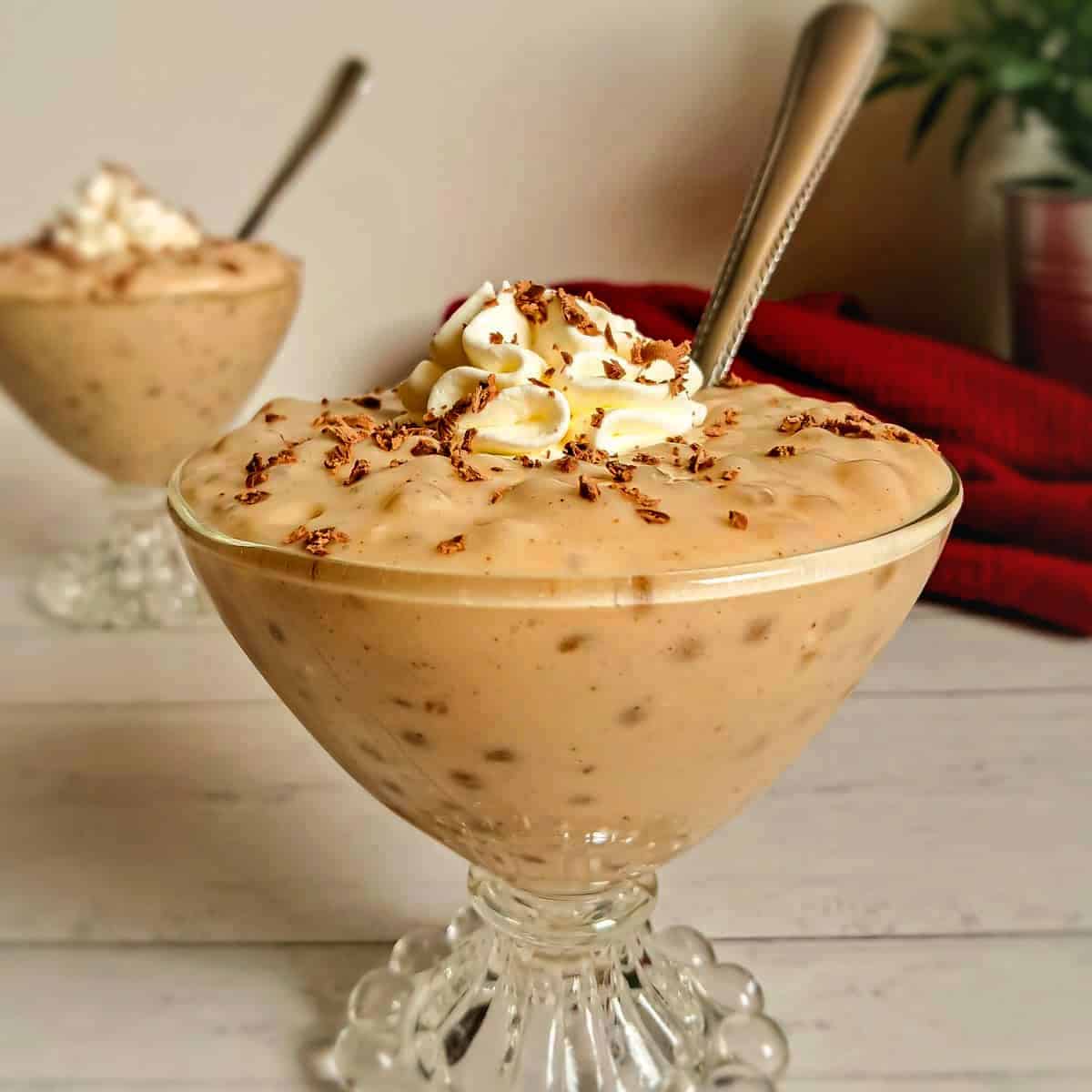 small bowls of homemade butterscotch tapioca pudding in goblet dishes with whipped cream and chocolate shavings on top.
