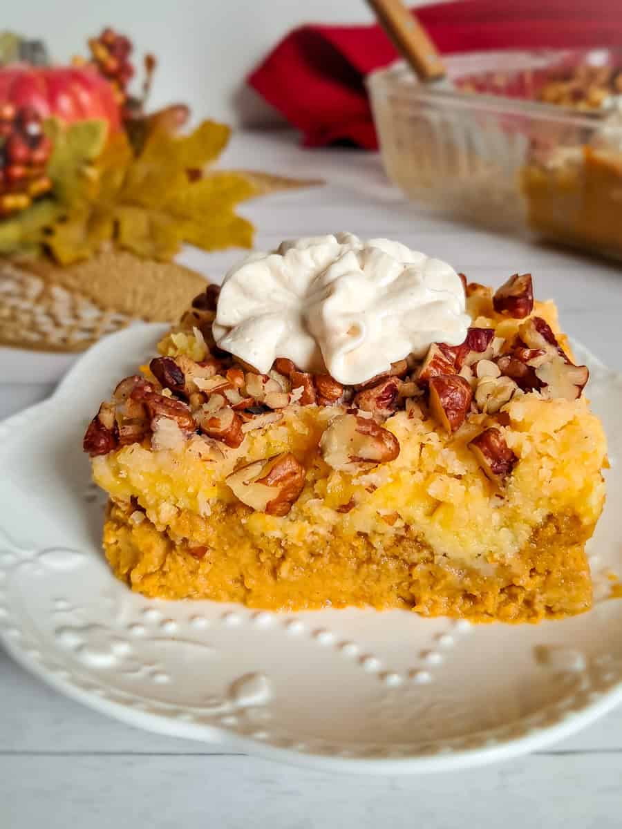 close-up look at a dish of Amish pumpkin cake dessert, with the remaining dish and pumpkin arrangement in the background.