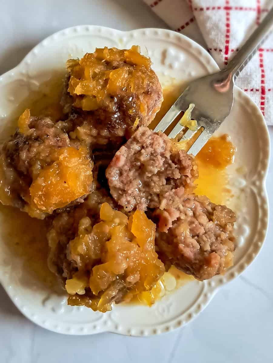 a plate full of pineapple hamballs. One is cut in half so you can see the inside.