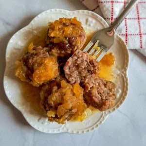 a plate full of pineapple glazed PA Dutch ham balls, one is cut open so that you can see the inside of the balls.
